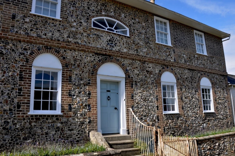 a stone house with a metal stair case and two windows