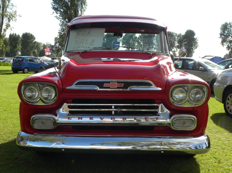 a red truck sitting on top of a green grass covered field