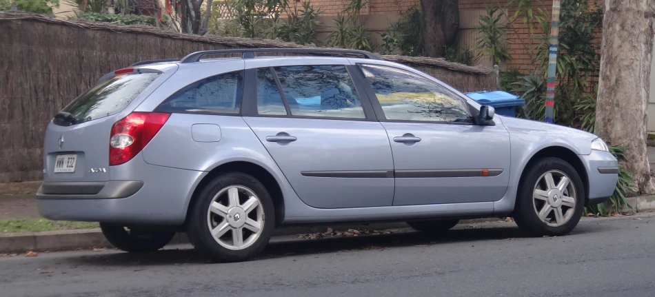 a gray car parked next to a fence and street