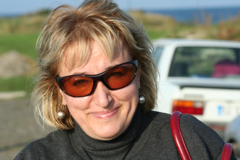 a blonde woman smiling next to some cars