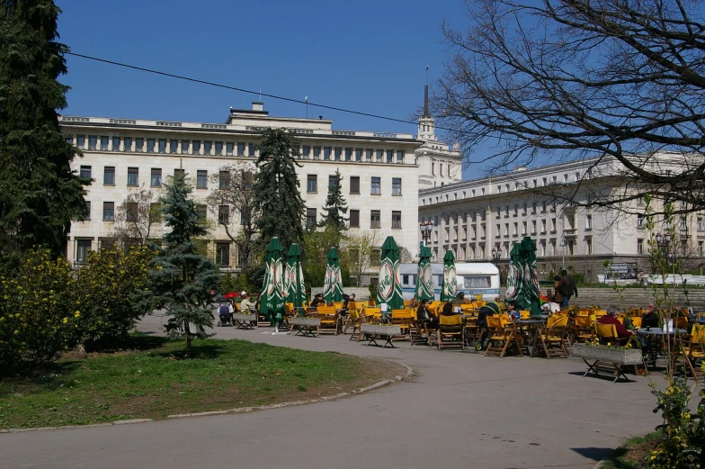 some buildings and many trees with yellow chairs