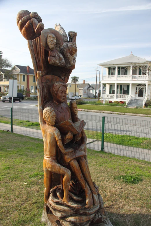 an art statue with figures in it's hands and a car in the background