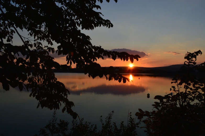 sunset from a hill above a lake with water reflection