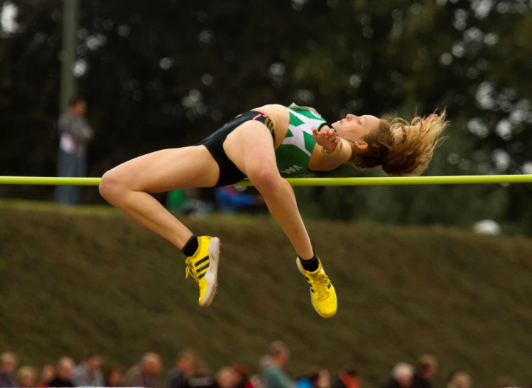 a woman is performing a high jump with an audience watching