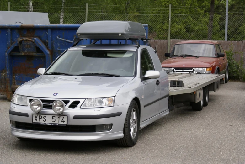 three cars, one of them has a trailer attached to the roof