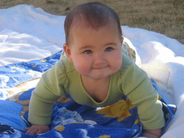 a little baby is laying on a blanket outside