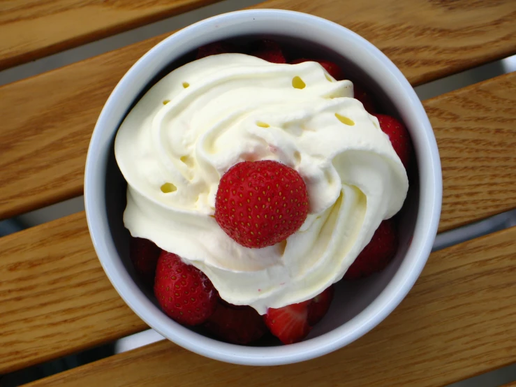 a bowl filled with strawberries on top of a wooden table