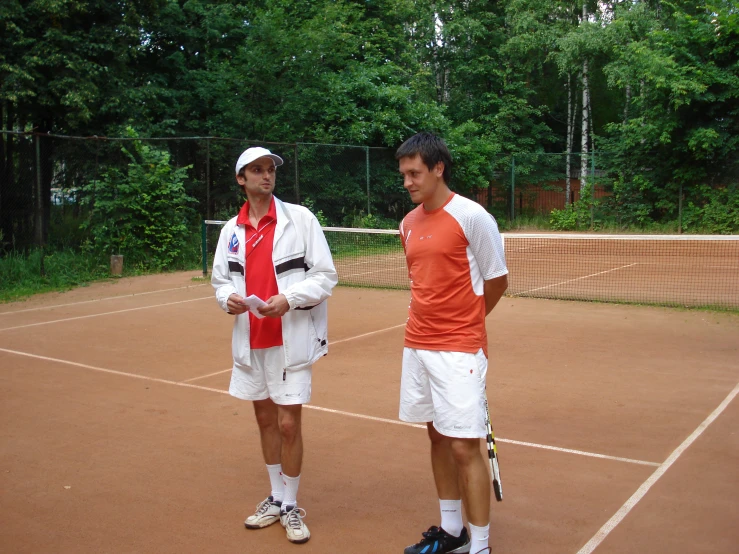 two tennis players stand on the court talking