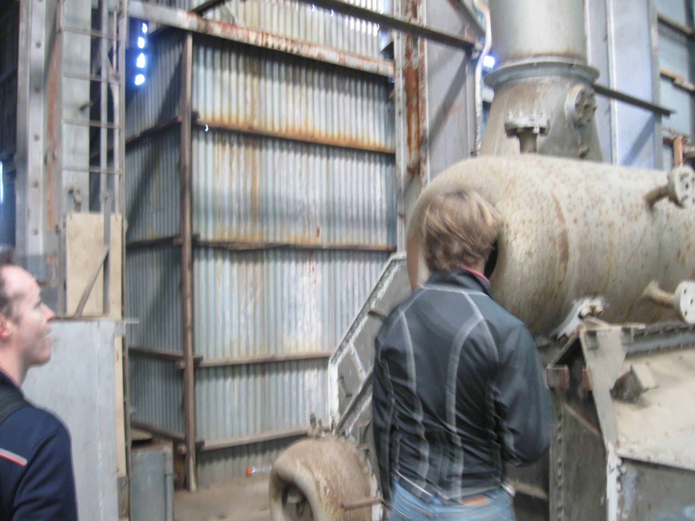 an industrial plant with men inside looking at a large piece of equipment