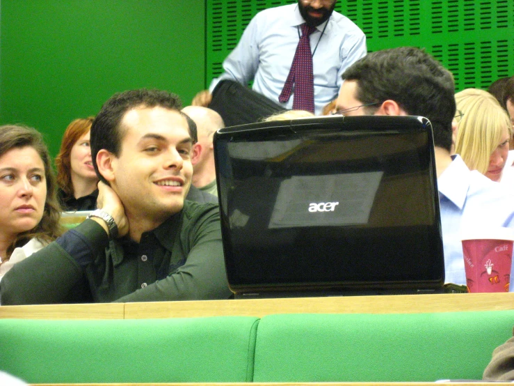 a group of people sitting next to each other in front of a laptop