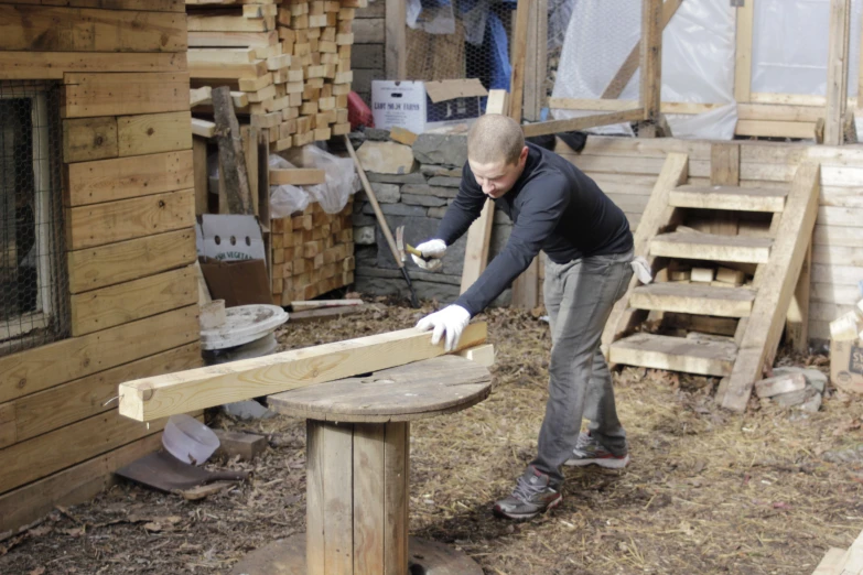 a man sanding a wooden structure in the middle of his yard