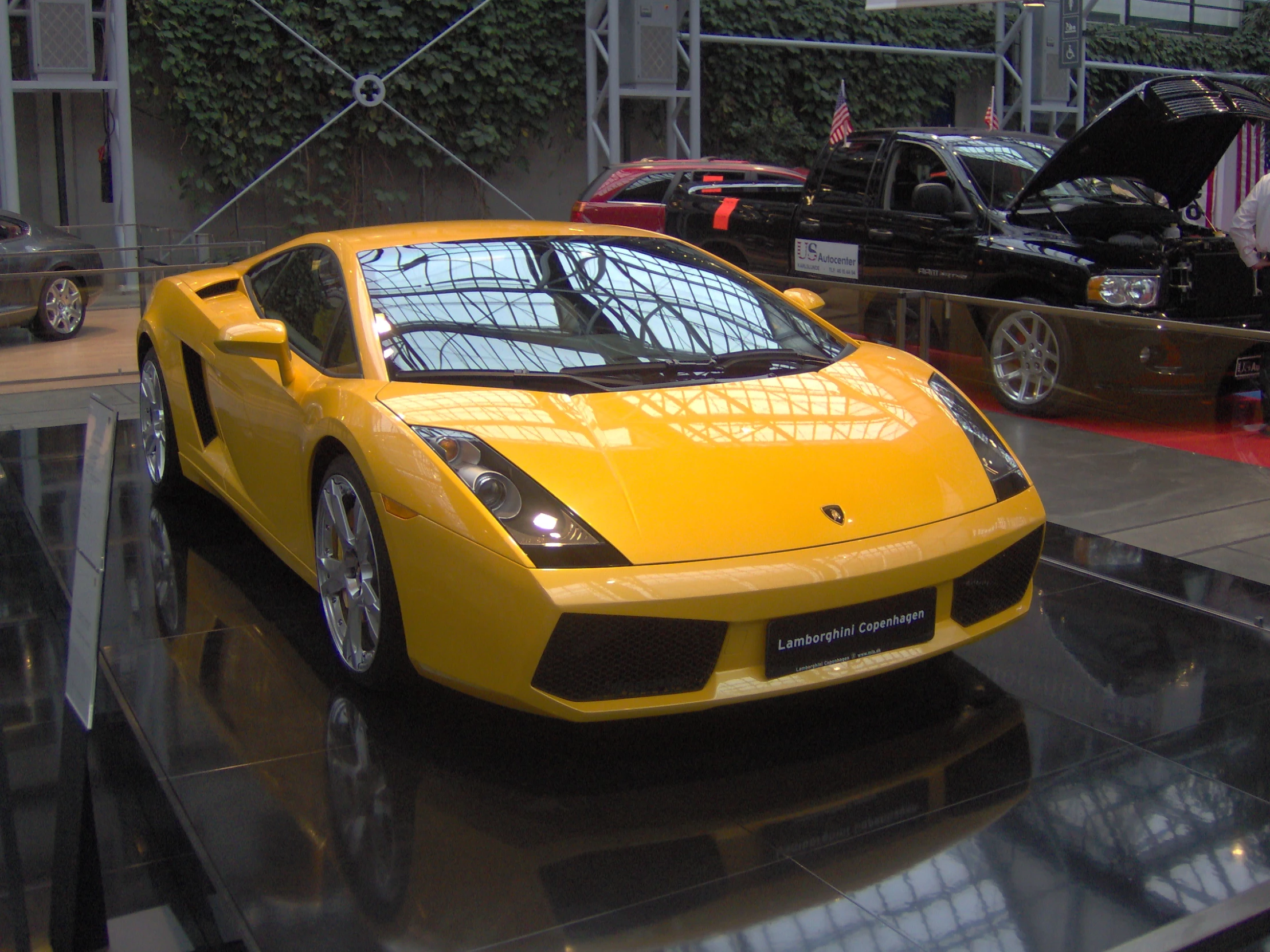 a yellow sports car sits in the center of a display