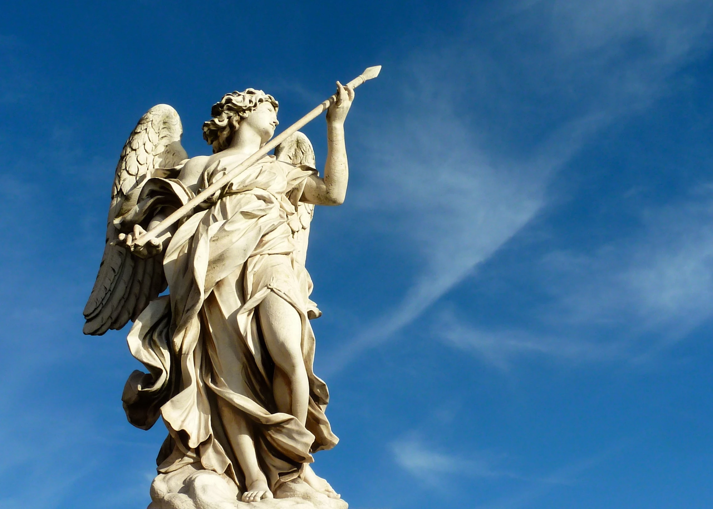 a statue with wings holding a spear in his hand