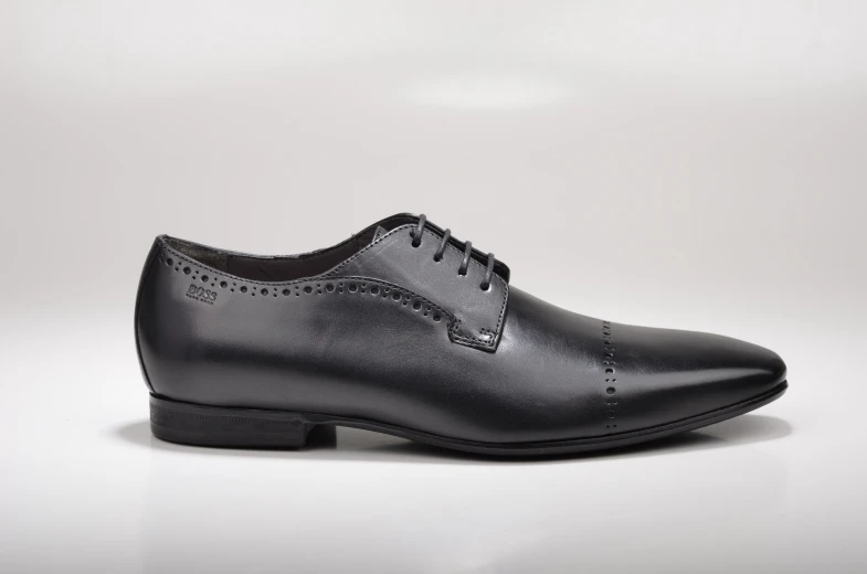 a pair of black brollar shoes on a white surface