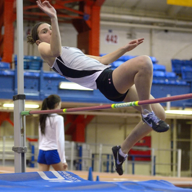 the young woman is jumping over the high bar