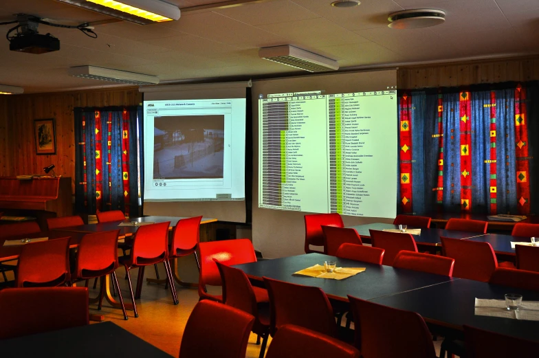 some red chairs a large projector and a projection screen