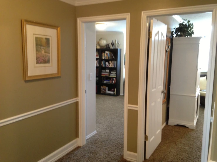 a hallway in a house with a book shelf and carpet