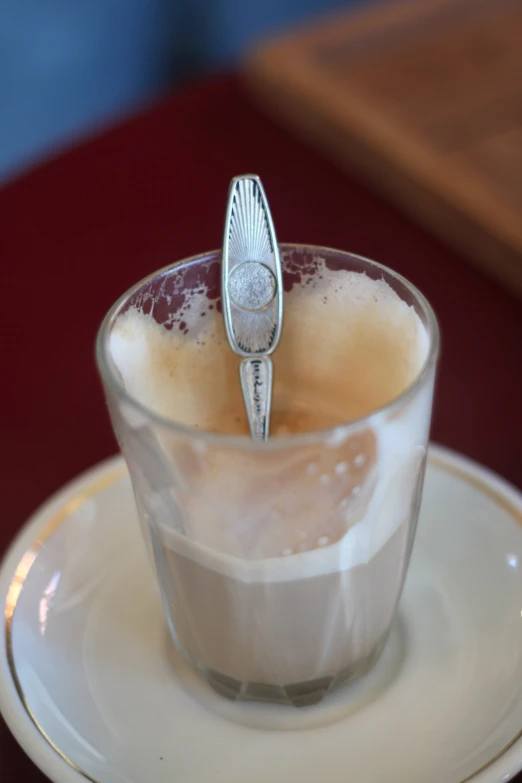 a spoon sticking out from inside a cup on top of a saucer