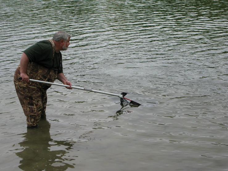 an old man standing in the water holding onto a fishing rod