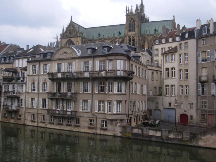 a river flows by two buildings in front of a cathedral