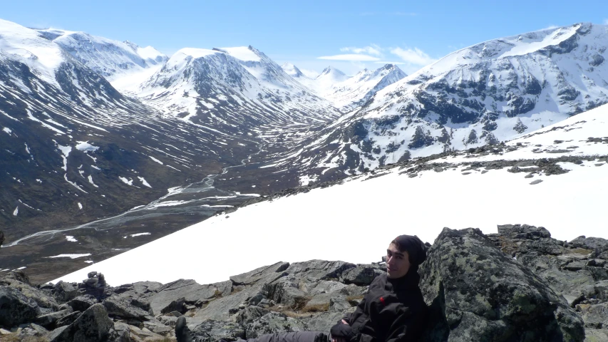 a person sitting on a large rock with a mountain view