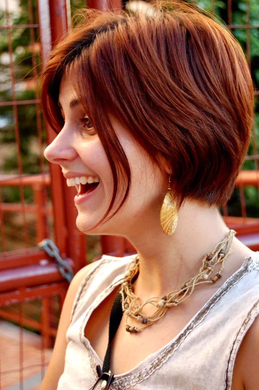 a smiling lady wearing a metal necklace and large earrings