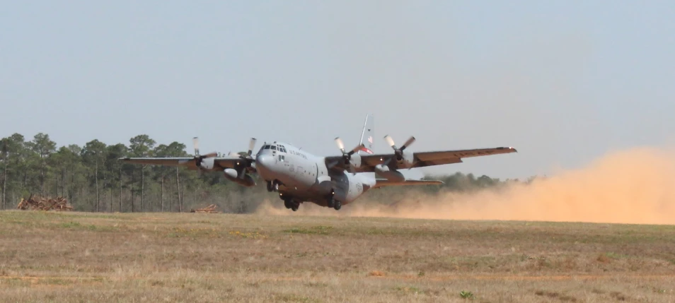 a large plane flying through a dry grass field