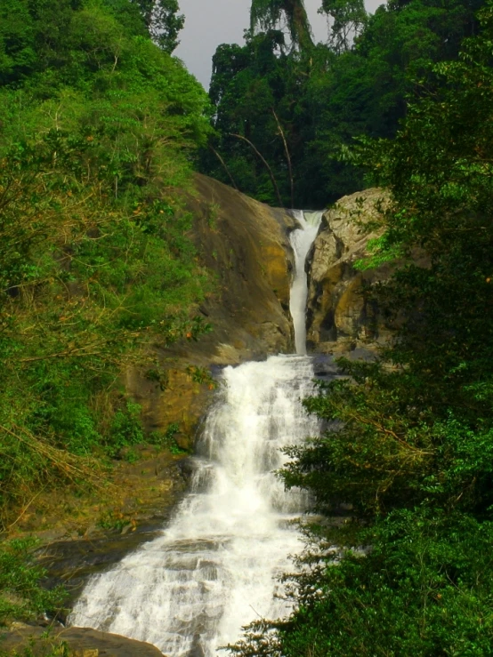 a waterfall flows into the green, forested waters