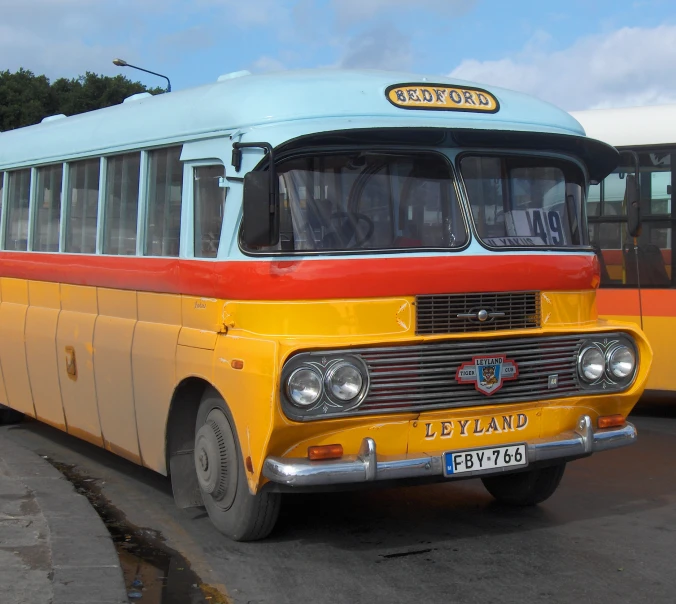 a yellow bus sitting in front of another bus on the road