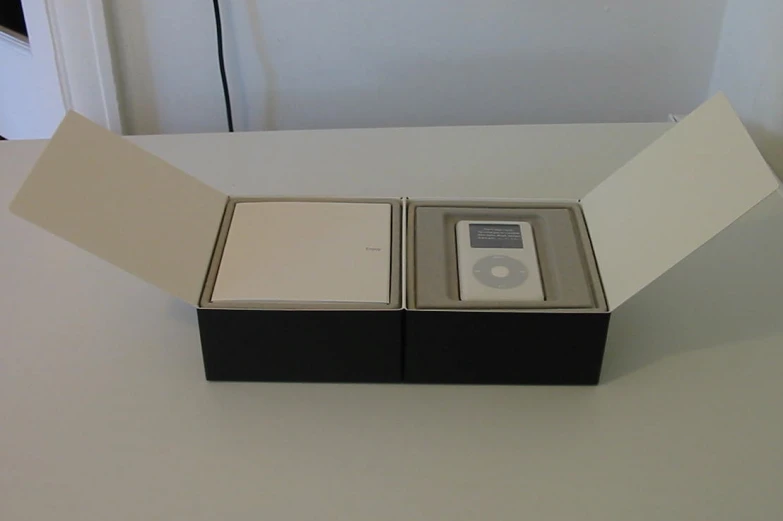 two apple ipods with boxes are sitting on the table