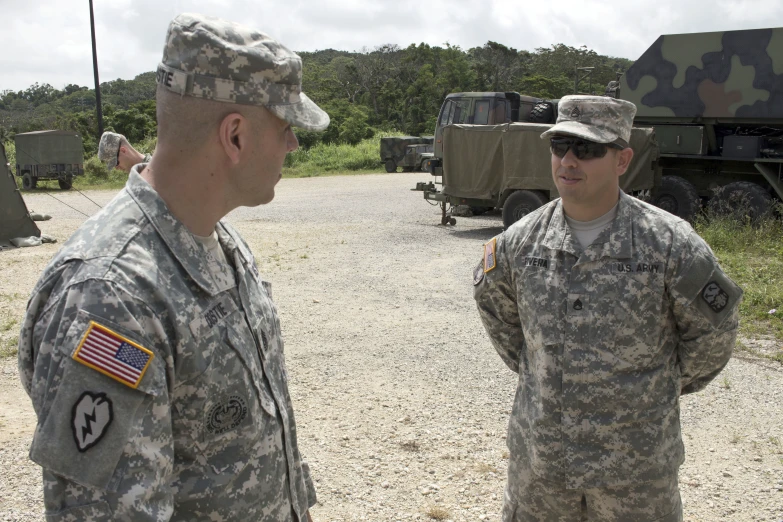 two men in camo wearing fatigues and military uniforms