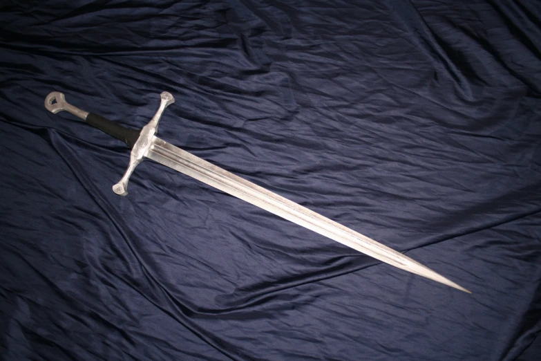 a sword sits on a blue blanket while lying down