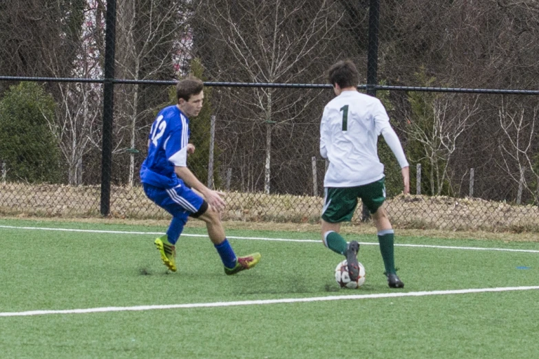 two boys playing soccer in the field during the day