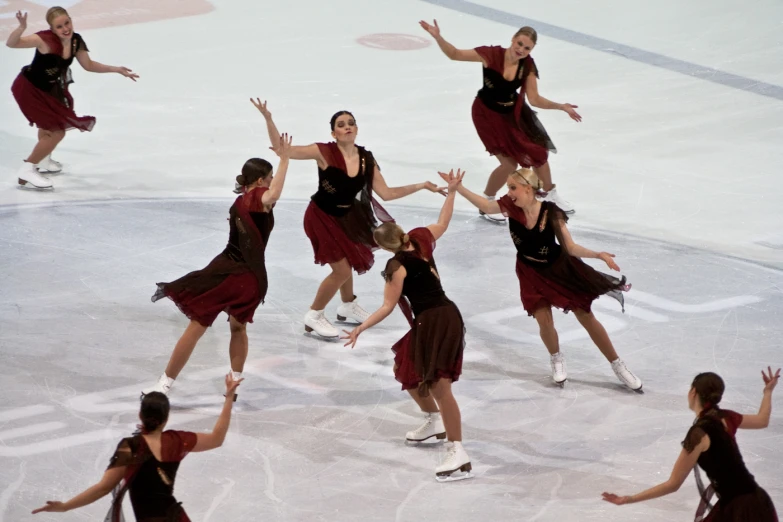 many women wearing black outfits are skating in a ice rink