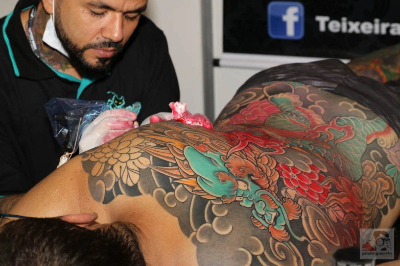 man getting tattooed by woman in a salon