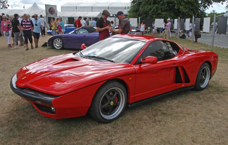 a red sports car parked on top of a grass covered field