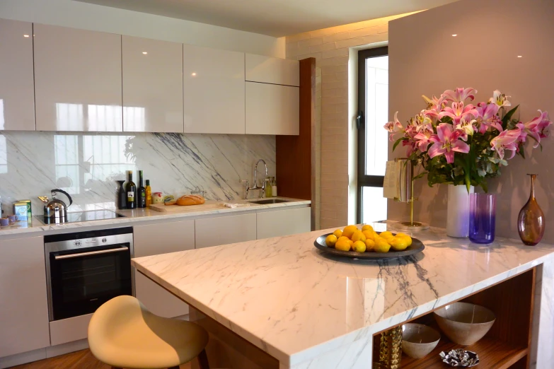 the white kitchen features a marble countertop and white cabinets