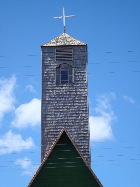 the cross on top of the tall tower has an open window