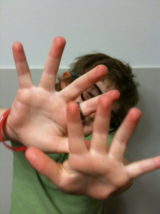 a boy wearing a celet holds his hands up in the air