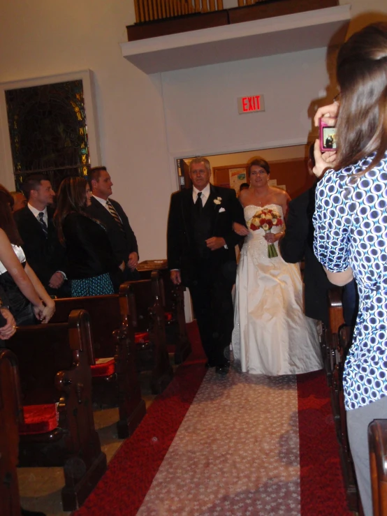 a woman walking down a church aisle holding a flower in her hand