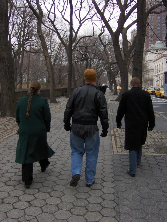 a man and two women walking across the sidewalk