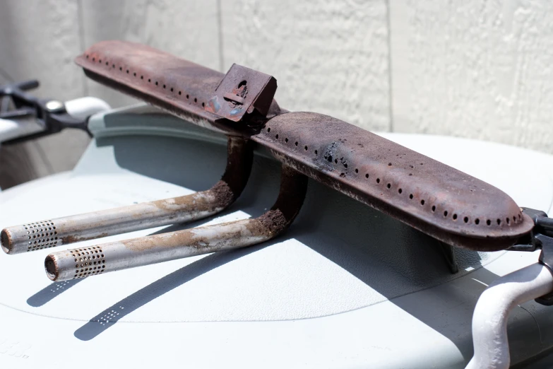 a dirty piece of old metal hanging from the back of a tank