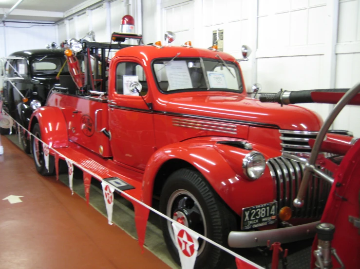 an old, bright red truck and a car in a building