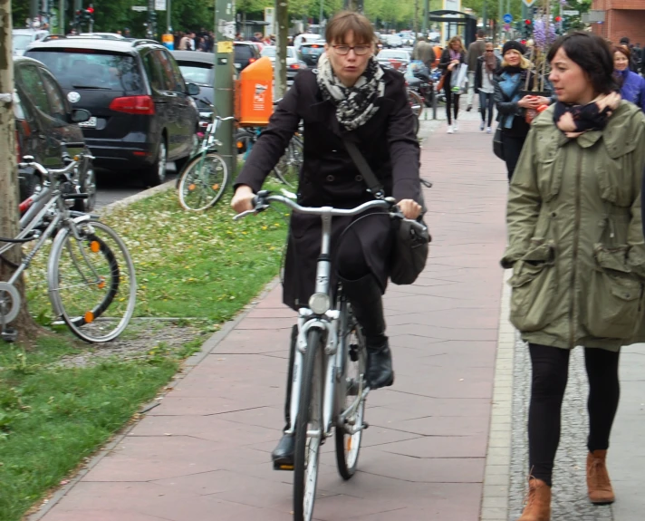 there is a woman walking and riding a bike on the sidewalk