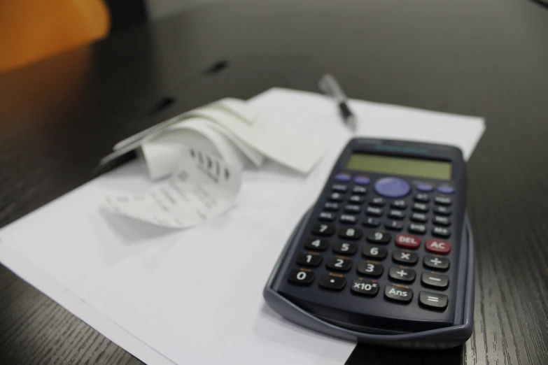 a calculator sitting on top of a table with papers next to it