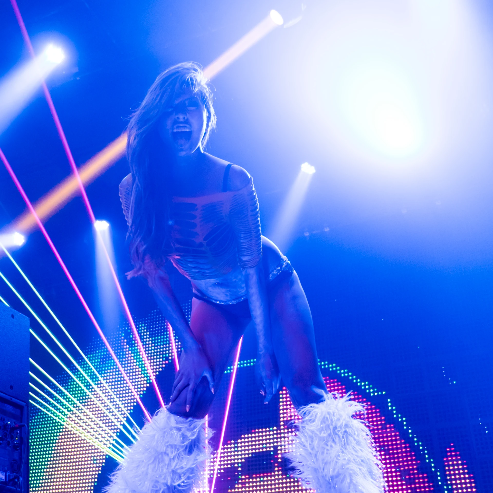 a person in a bodysuit on top of a pole with lights behind them