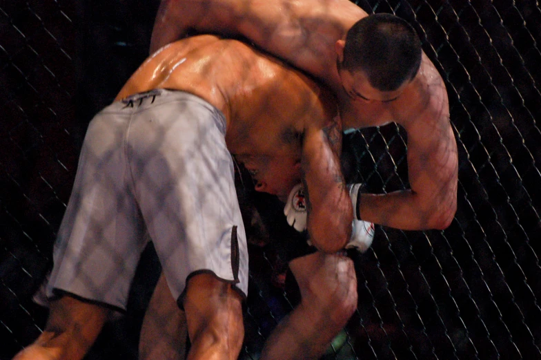 two men wrestling in a caged area during a tournament