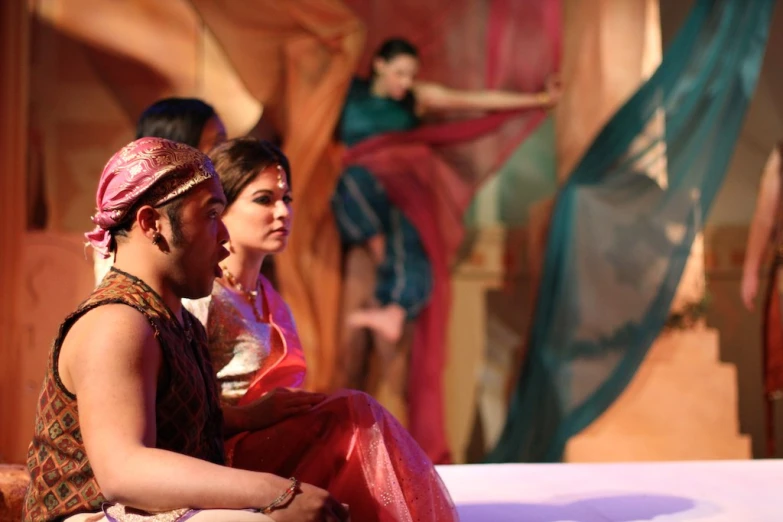 three women in sari sitting on the stage
