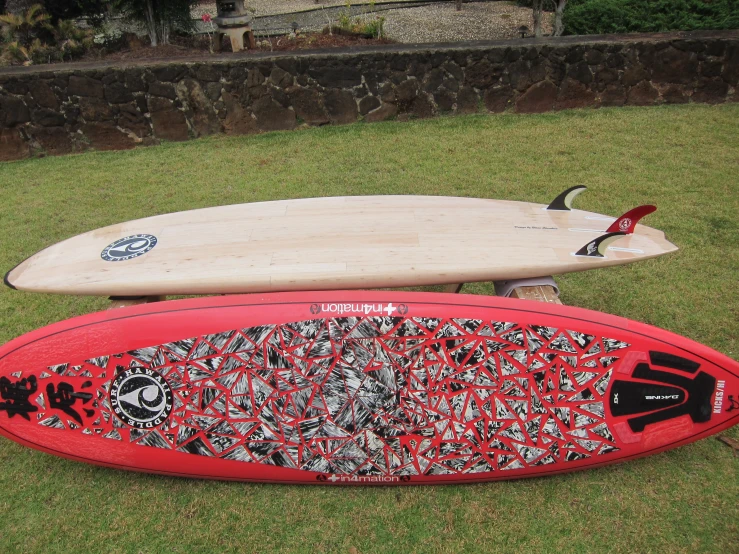 two surfboards sitting in the grass with designs on them