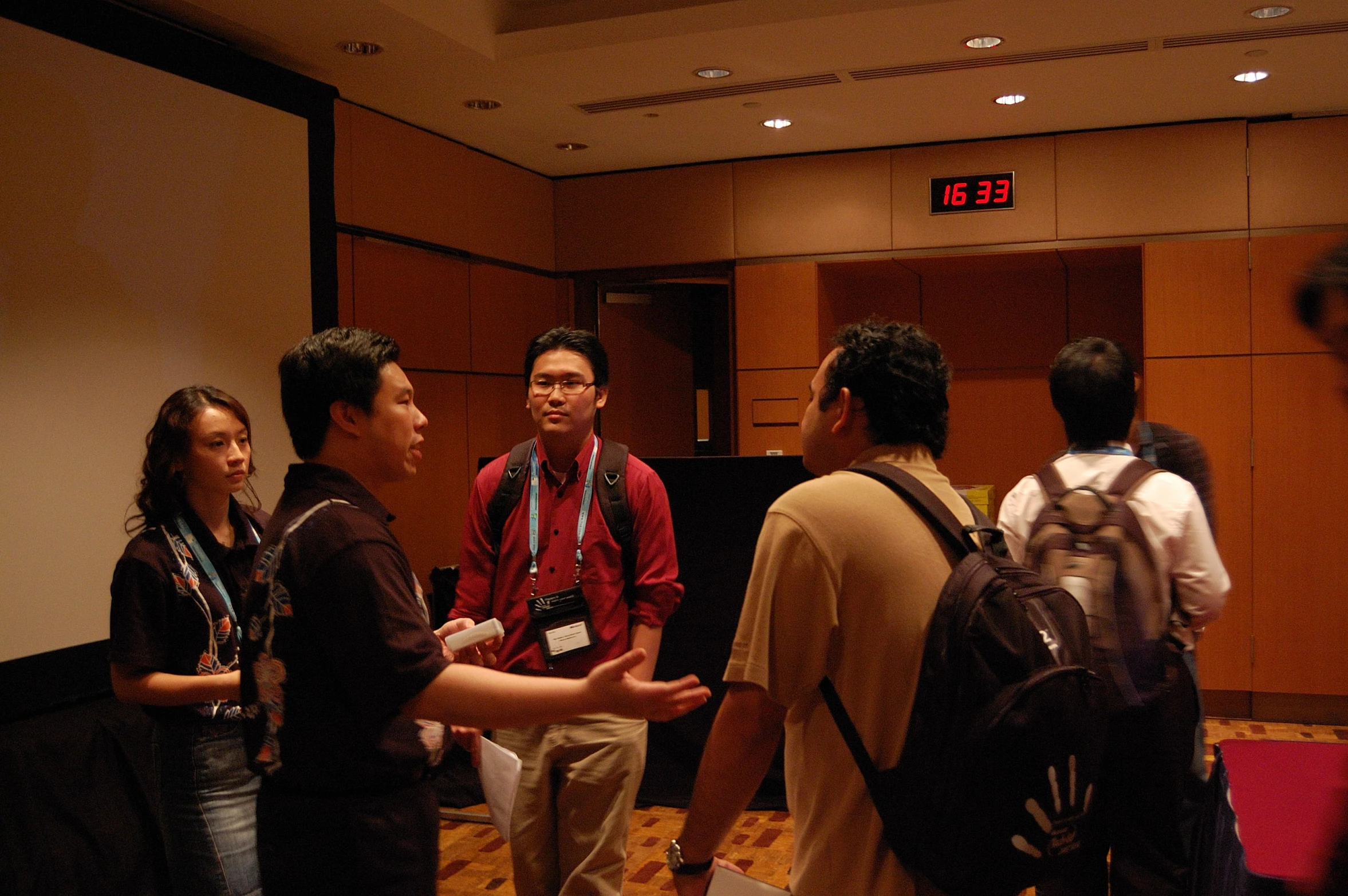 several people are standing in a conference hall and talking